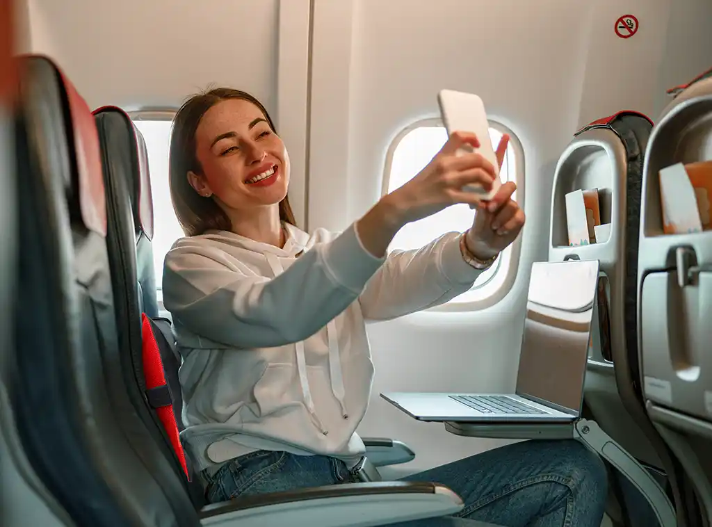 woman taking selfie on airplane with premium adjustable travel pillow